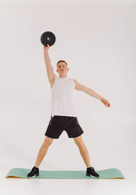 Athletic young man doing workouts at home, man doing training, warm up before weight exercise.