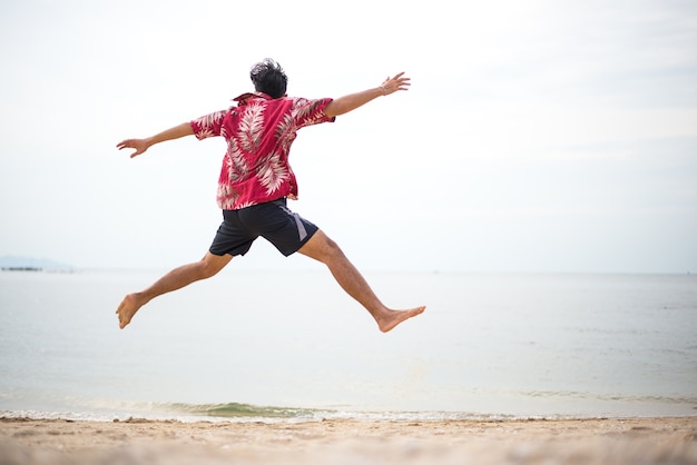 Foto giovane atletico godendo l'estate, saltando in una spiaggia tropicale