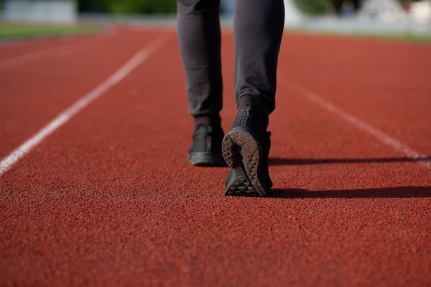 Athletic young man jogging at the red running track. Space for text