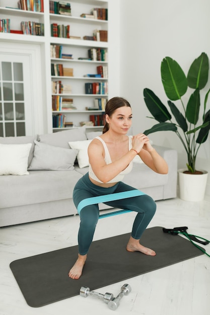 Athletic young woman doing morning exercises squatting alone in the living room serious girl