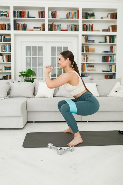 Photo athletic young woman doing morning exercises squatting alone in the living room