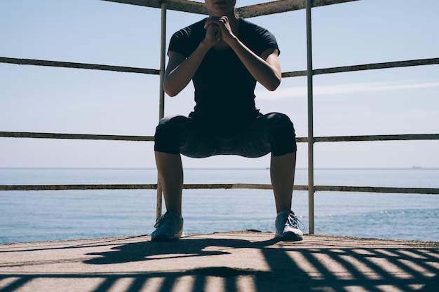 Athletic young woman doing sit-ups in the morning against the of the sea, close-up