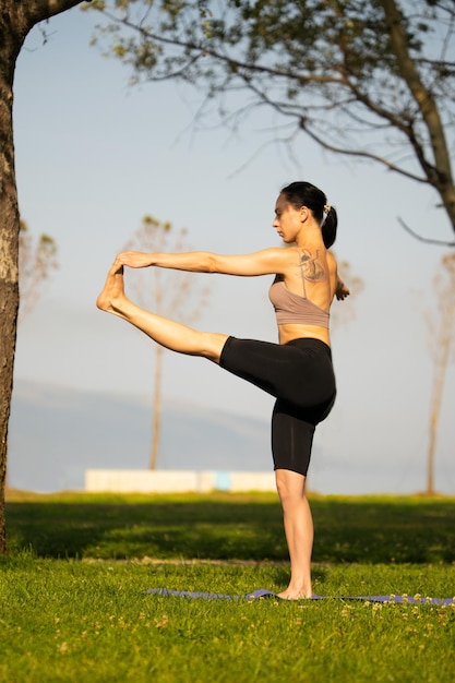 Giovane donna atletica che fa yoga nel parco al mattino