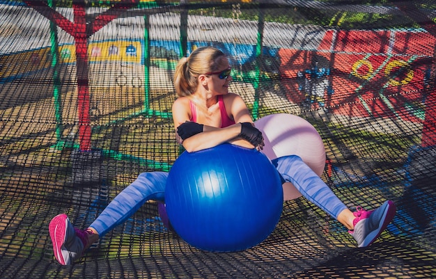 Athletic young woman exercising using fitball in a training camp