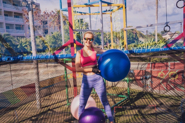 Athletic young woman exercising using fitball in a training camp