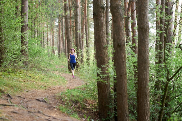 Athletic young woman in pink sneakers run in spring forest