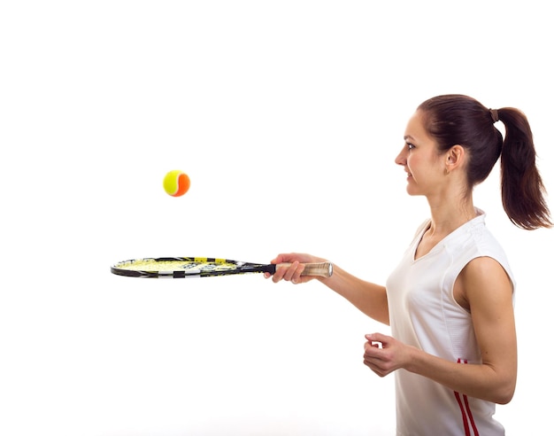 Спортивная молодая женщина в белой спортивной рубашке с темным хвостиком держит теннисную ракетку и оранжевый мяч