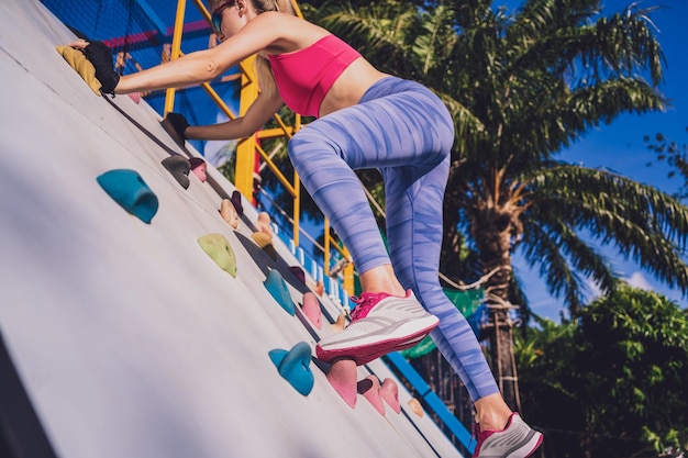 Athletic young woman working out and climbing at the artificial rock in training camp