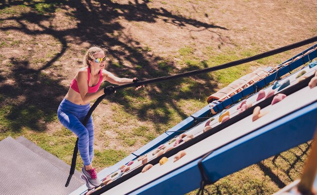 Athletic young woman working out and climbing a ropes at the rope training camp