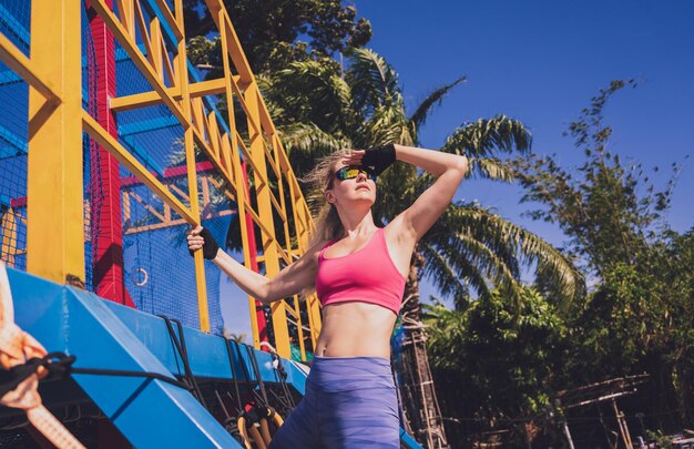 Athletic young woman working out and climbing a ropes at the rope training camp