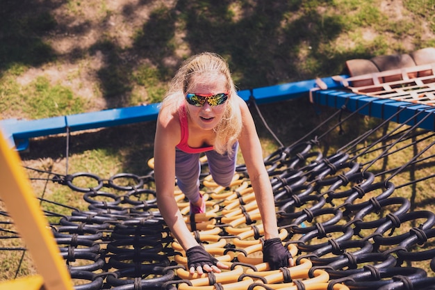 Athletic young woman working out and climbing a ropes at the rope training camp