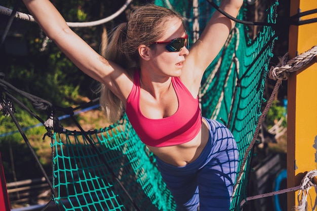 Спортивная молодая женщина тренируется в тренировочном лагере на веревке