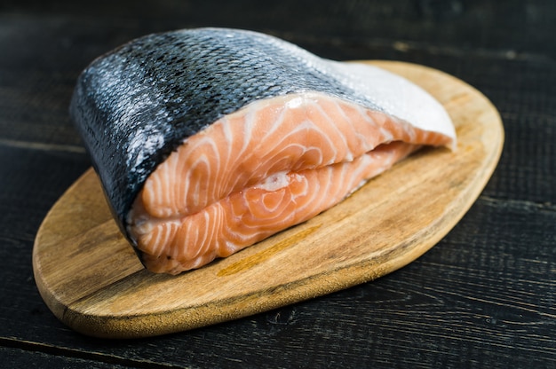 Salmone crudo atlantico, bistecca su fondo di legno nero