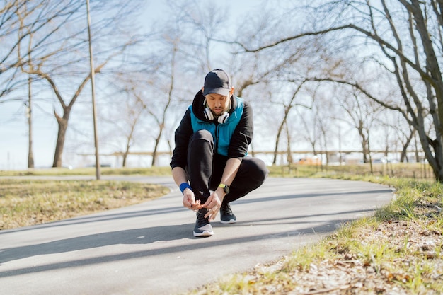 Atleet bindt sportschoenen vast voordat hij jogt op straat in een stadspark