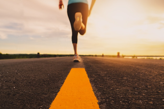 Atleet die op het wegspoor lopen in zonsondergang opleiding. bewegingsonscherpte van vrouw buitenshuis oefenen