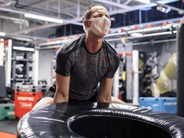 Foto atleet die tijdens een pandemie in de sportschool traint en een beschermend gezichtsmasker draagt