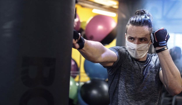 Atleet die tijdens een pandemie in de sportschool traint en een beschermend gezichtsmasker draagt