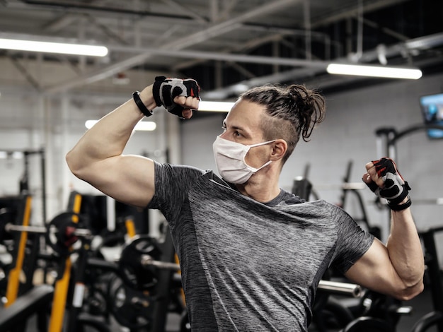 Atleet die tijdens een pandemie in de sportschool traint en een beschermend gezichtsmasker draagt