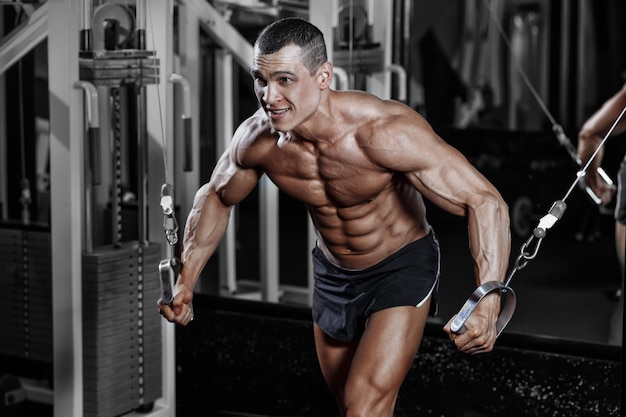 Foto atleet, gespierde bodybuilder, man in de sportschool die met een simulator traint.