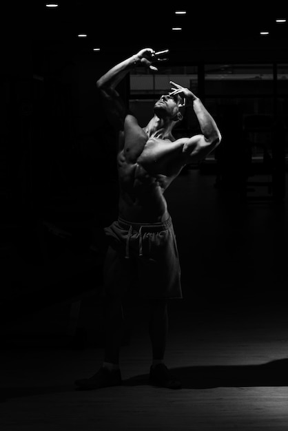 Atleet gespierde brute bodybuilder emotioneel poseren in een donkere sportschool