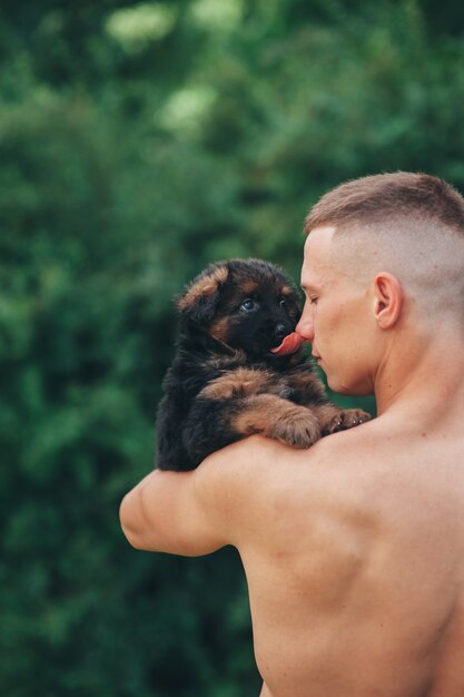atleet jongen bedrijf in haar armen, puppy Duitse herder