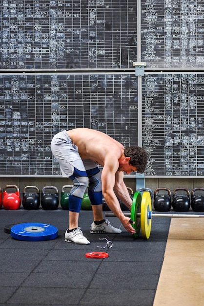 Atleet laadt plaatgewichten op een halter in een sportschool ter voorbereiding op zijn bodybuilding-training in een gezondheids- en fitness- of trainingsconcept