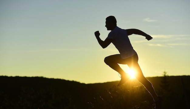 Atleet loopt op zonsondergang hemel achtergrond kopie ruimte