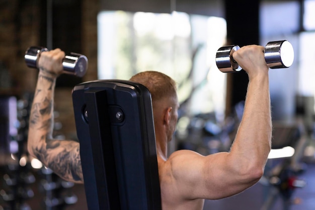 Atleet man bodybuilder trainen training in de sportschool met halter gewicht oppompen