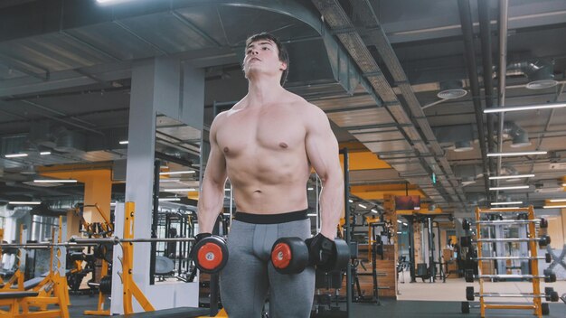 Atleet man tillen halters zonder shirt in de sportschool, close-up