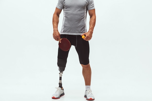 Atleet met een handicap of geamputeerde geïsoleerd op een witte studio achtergrond. Professionele mannelijke tafeltennisser met beenprothese training in studio. Gehandicapte sport en gezonde levensstijl concept.
