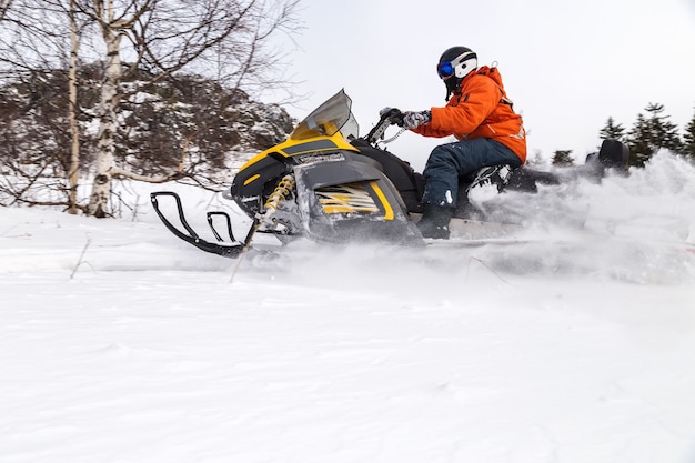 Atleet op een sneeuwscooter die zich in het winterbos beweegt