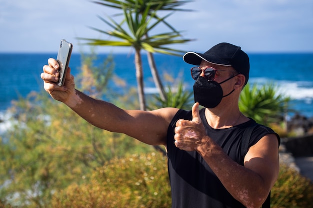 Atleet op een strand die een selfie maakt met een masker op