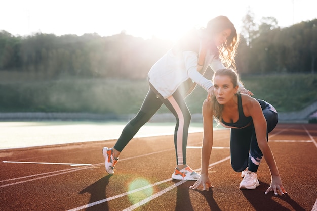 atleet training met personal trainer op atletiekbaan in de ochtend lichte actieve fitness vrouwen