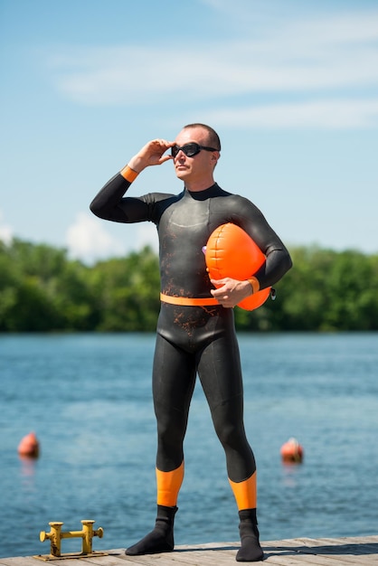 Foto atleet zwemmer in een wetsuit met een boei zet een bril op