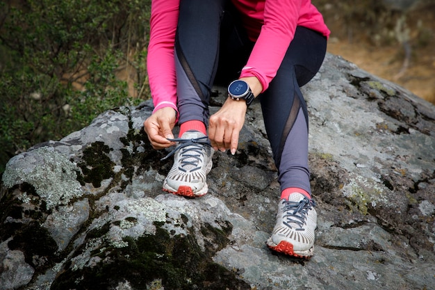 Photo atleta atandose los cordones de los tenis a la orilla de un lago despues de correr en la naturaleza