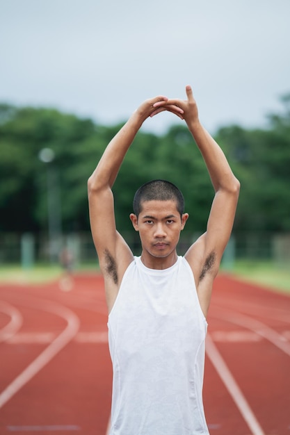 Atleten sport man loper dragen witte sportkleding om uit te rekken en op te warmen voordat ze oefenen op een atletiekbaan in een stadion Runner sport concept