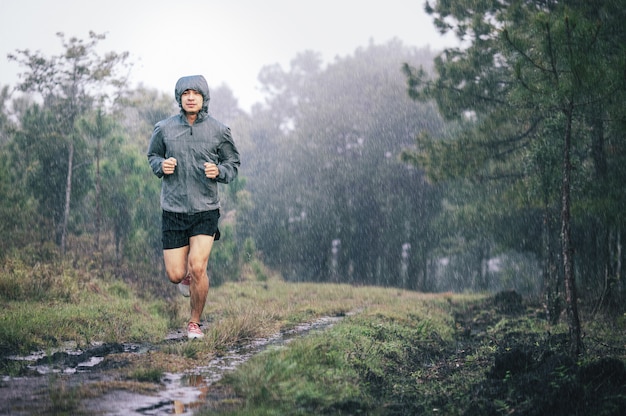 Atletenagent in grijze sportjas bossleep in de regen