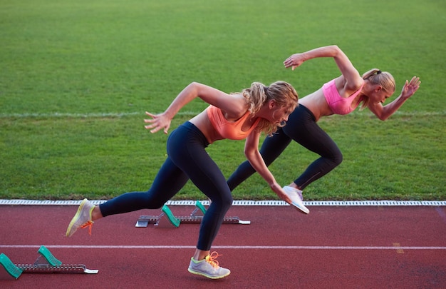 atletenvrouwengroep die op atletiekracebaan op voetbalstadion loopt en concurrentie en leidingsconcept in sport vertegenwoordigt