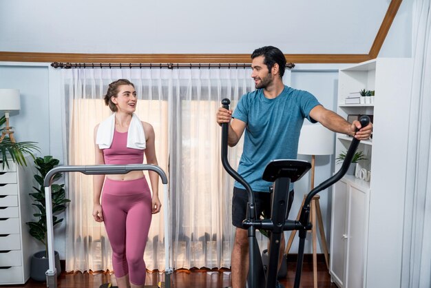 Foto atletisch en sportief paar dat op een elliptische hardloopmachine loopt bij gaiety home