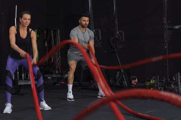 Atletisch jong koppel met slagtouw doen oefening in functionele training fitness gym