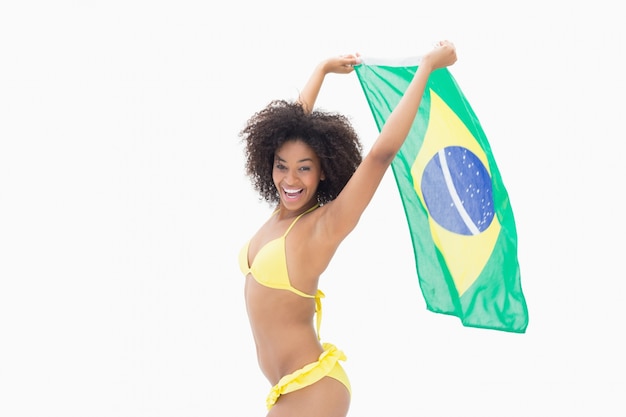 Atletisch meisje in de gele vlag van Brazilië van de bikiniholding