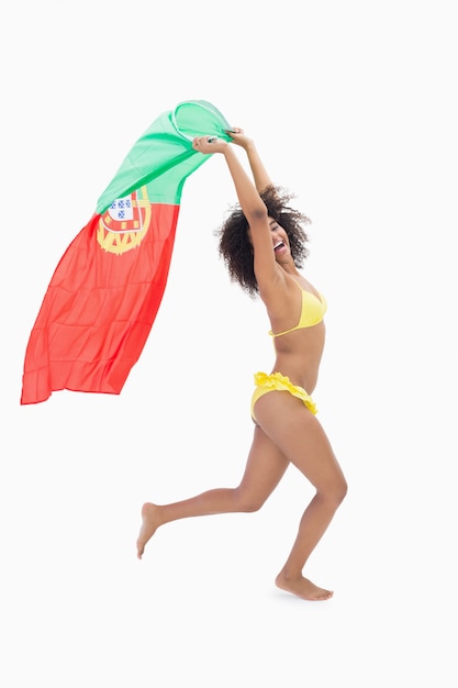 Atletisch meisje in de gele vlag van Portugal van de bikiniholding