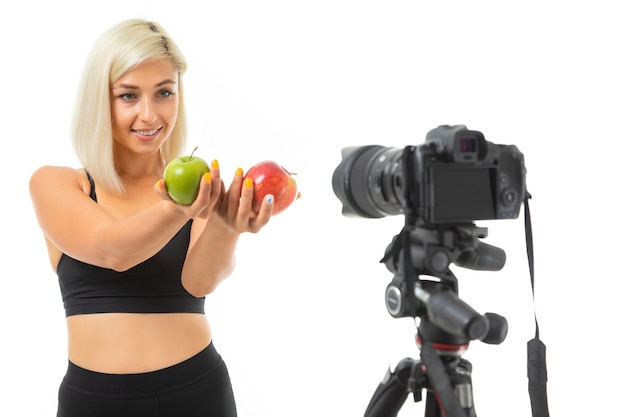 Atletisch meisje in een sport-uniform toont appels op een camera