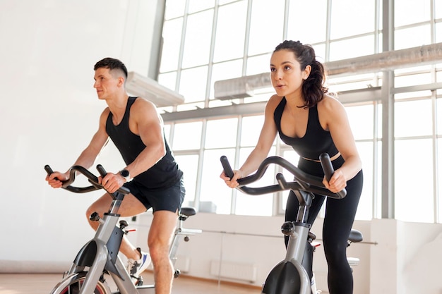 atletisch paar fietsers trainen in de fitnessruimte op een statische fietssimulator