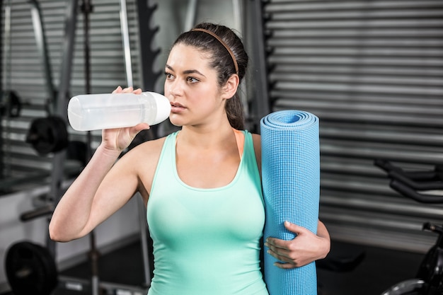 Atletisch vrouwen drinkwater bij crossfitgymnastiek