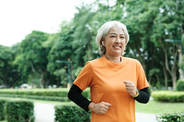 Atletische Aziatische senior vrouw die buiten joggen in park