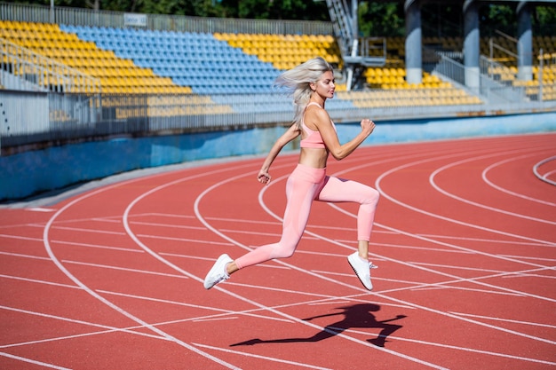 Atletische dame lopen op stadion atletiekbaan vrouwelijke atleet klaar voor sprint sport training trainer of coach opleiding marathon energieke en sportieve sexy fitness vrouw in sportkleding