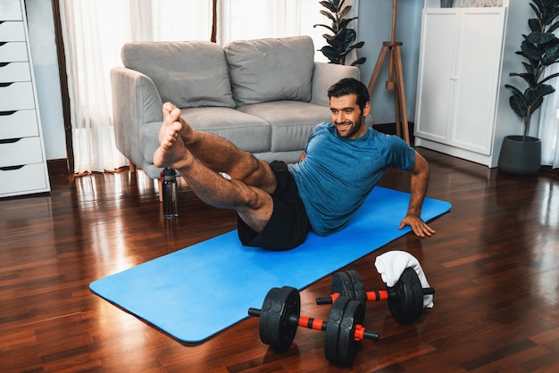 Atletische en sportieve man doet crunch op fitness mat bij gaiety home