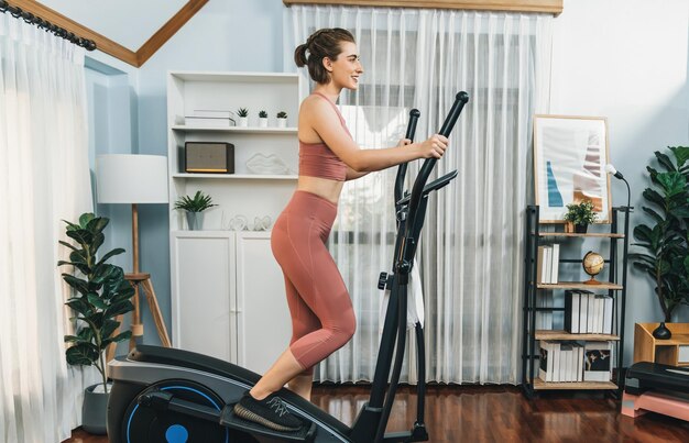 Atletische en sportieve vrouw loopt op een elliptische loopmachine in het huis van gaiety