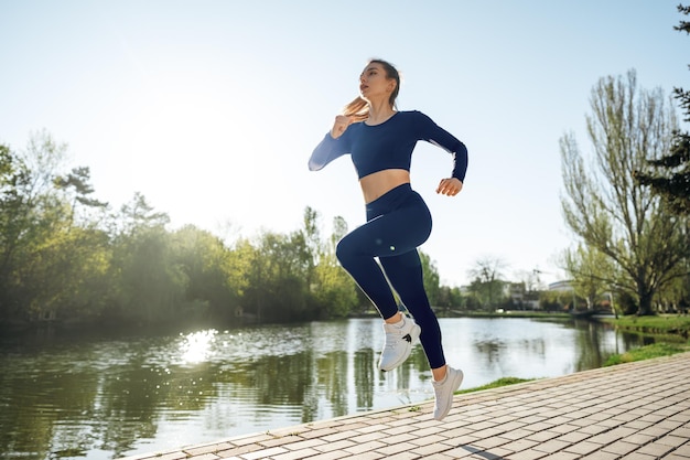 Atletische fitte jonge vrouw die vroeg in de ochtend jogt in het park